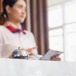 Hotel front desk staff using a tablet next to a service bell
