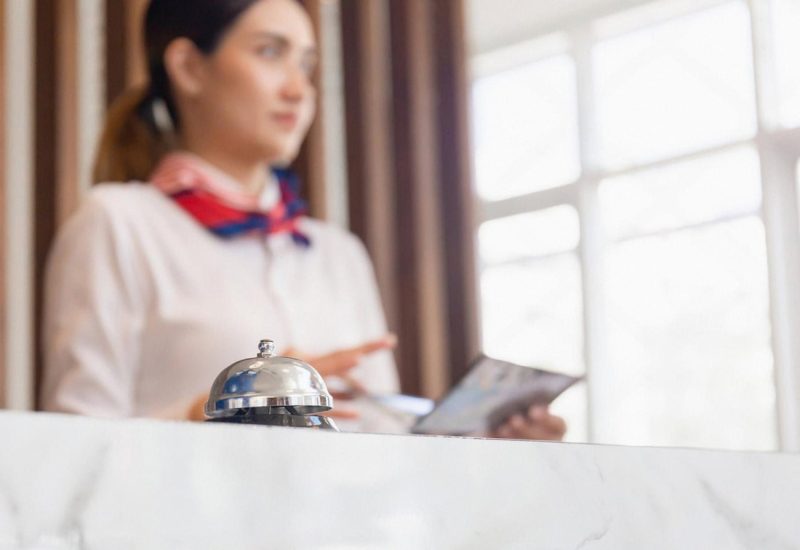 Hotel front desk staff using a tablet next to a service bell