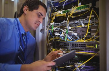 IT engineer inspecting a server rack with a tablet during a routine maintenance check at a Dubai office