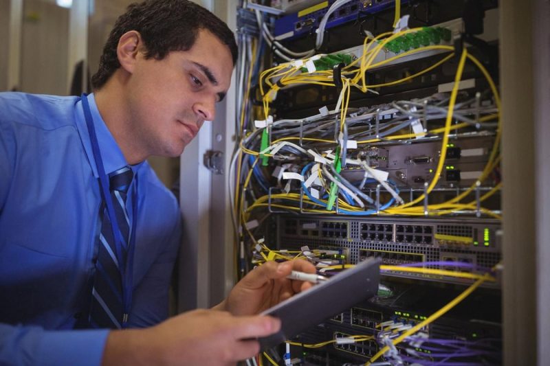 IT engineer inspecting a server rack with a tablet during a routine maintenance check at a Dubai office